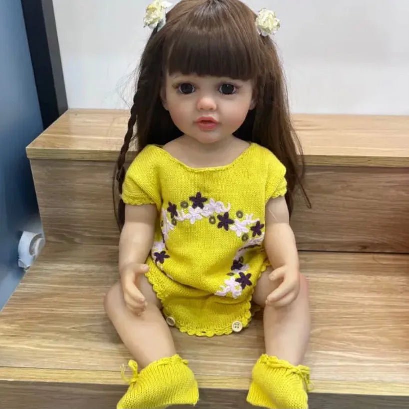 Betty Princess full silicone Reborn Doll in a yellow outfit posed on wood for nursery display, cuddling, and keepsake collecting.