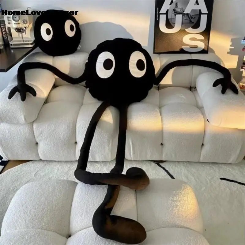 Black coal ball plush toy with large eyes styled as a sofa pillow for living room decor.
