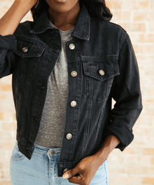 Person wearing a black denim jacket over a gray shirt.