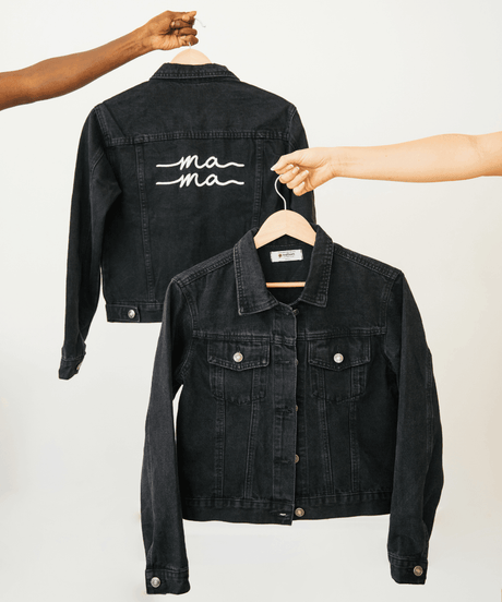 Black denim jacket with 'ma ma' embroidery on a hanger.