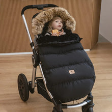 Child seated in the black puffer stroller footmuff, an insulated cover for school runs and cold-weather walks.