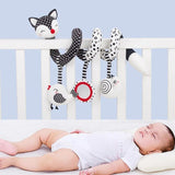 Baby lying in a crib with colorful baby toys hanging over the side.