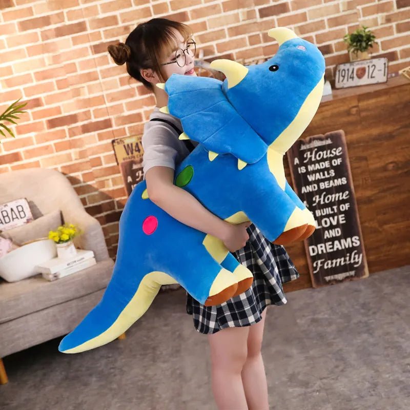 Blue Stegosaurus dinosaur plush doll held in a living room, sized for cuddling on the sofa and floor play.