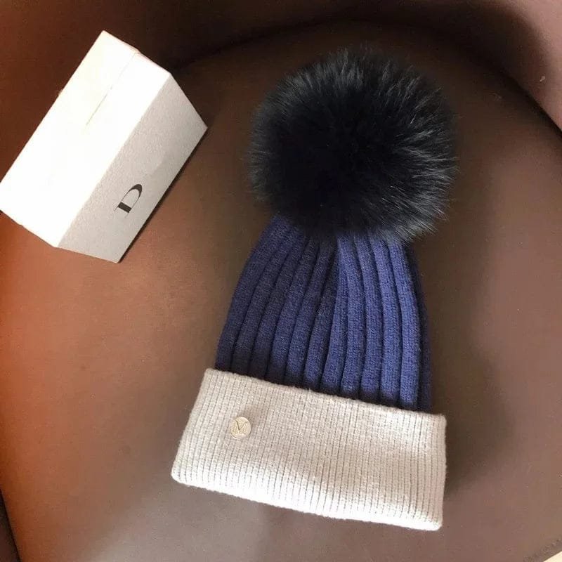 Blue and white knit beanie with black pom pom for boys winter wear, sledding, and outdoor playtime.