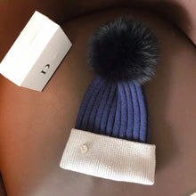 Blue and white knit beanie with black pom pom for boys winter wear, sledding, and outdoor playtime.