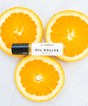 Oil roller bottle labeled 'Sunflower' on sliced oranges.
