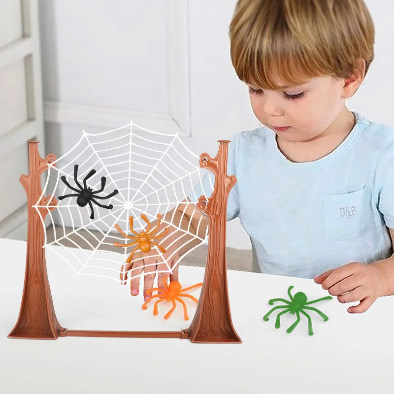 Boy playing the spider web game with black and orange spiders on the web and a green spider on the table