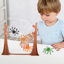 Boy playing the spider web game with black and orange spiders on the web and a green spider on the table