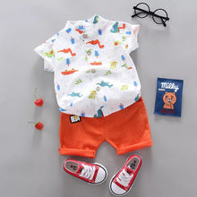 Children's outfit with a cartoon-patterned shirt, orange shorts, red sneakers, and a small bag.