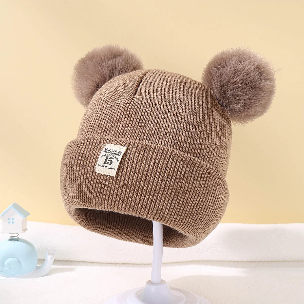 Brown Warm Knitted Baby Beanie detail view showing pom poms for cosy winter warmth on daily pram outings.