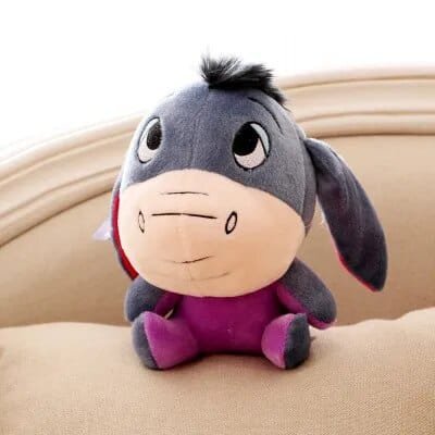 Plush toy resembling a donkey with a purple outfit on a beige surface