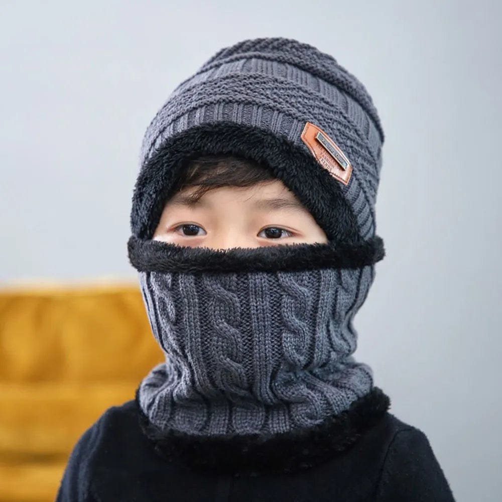 Person wearing a gray knitted hat and scarf set against a plain background