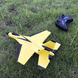 Yellow and black remote control airplane on grass with a controller nearby