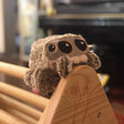Plush sloth toy on a wooden surface with a blurred background