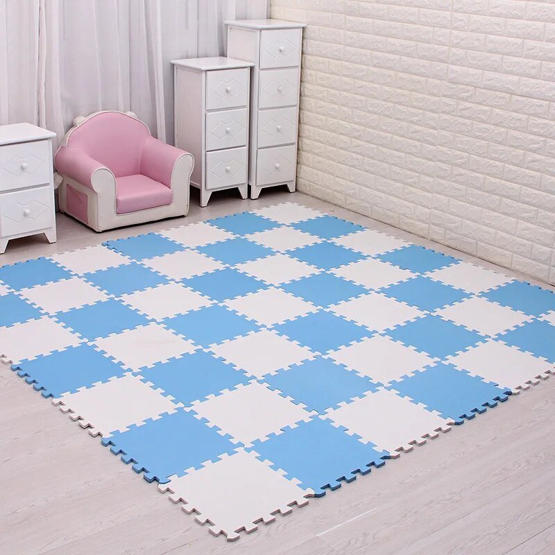 Blue and white checkered foam mats on a wooden floor with a pink chair and white dresser in the background.