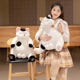 Person holding a large plush cat toy with another plush cat toy on a chair.