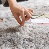 Close-up of a hand touching a textured gray carpet