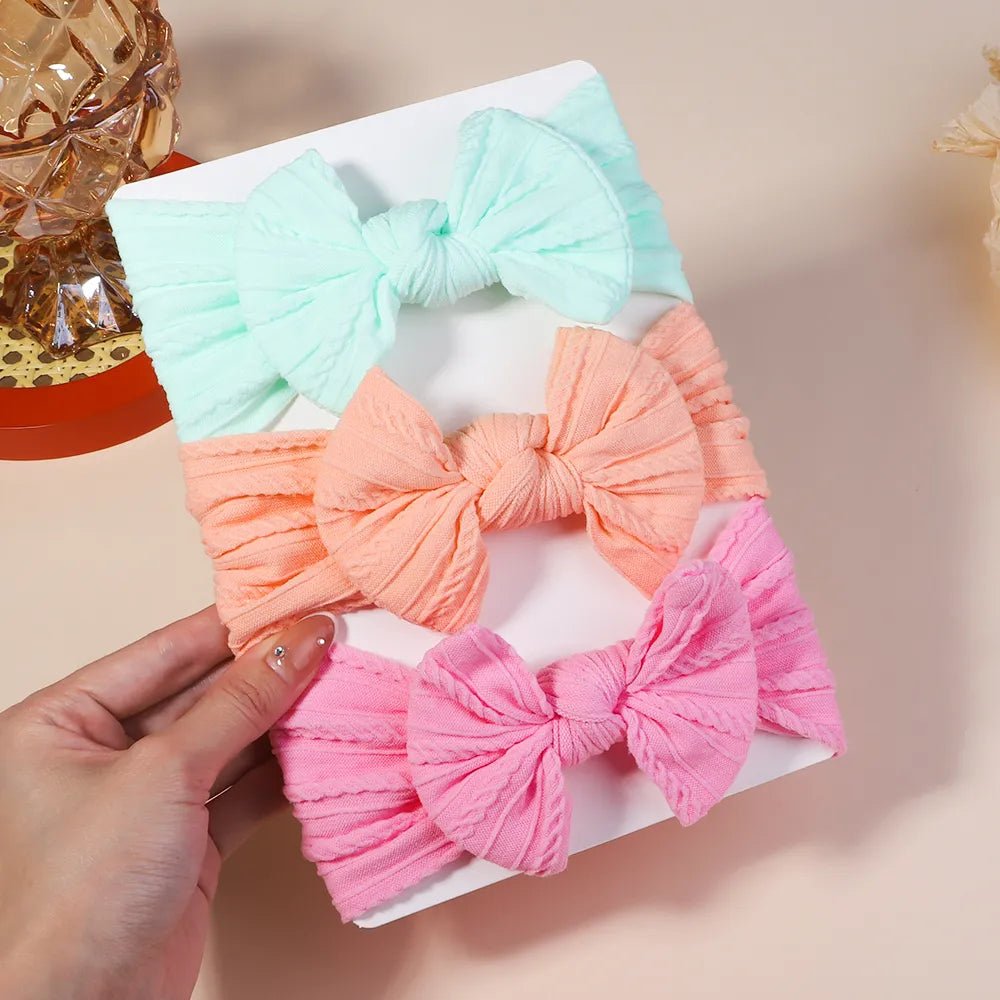 Set of three colorful hair bows held by a hand.