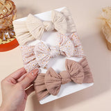 Set of decorative bows on a white plate with a hand holding one bow, against a neutral background.
