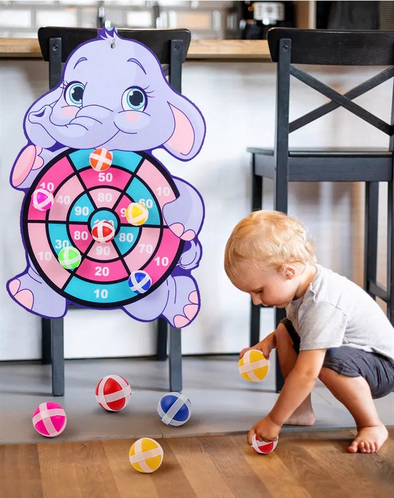 Child playing with a dartboard shaped like an elephant.