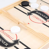 Close-up of a foosball table with white and black balls on a light wood surface.