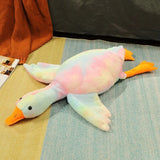 Plush toy duck on a textured surface with an orange blanket and magazine in the background