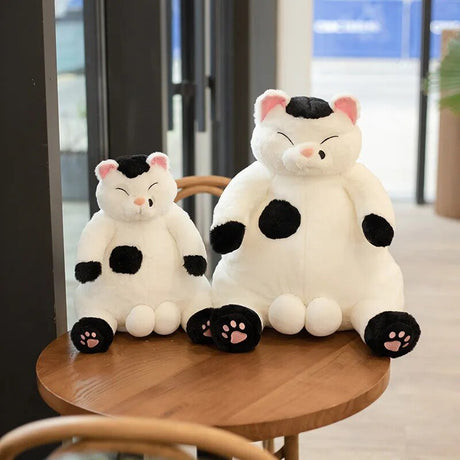 Two plush cat toys with black and white patterns on a wooden table.