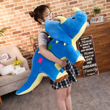 Person holding a large blue dinosaur plush toy in a living room setting.