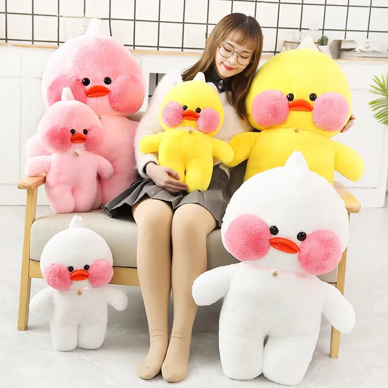 Woman sitting on a chair surrounded by large plush ducks in various colors.