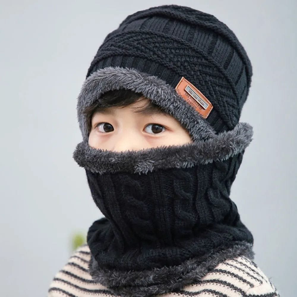 Person wearing a black knit beanie and scarf set with gray trim on a plain background