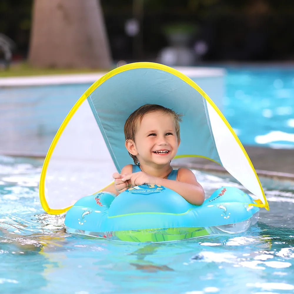 Child playing in the pool with a blue inflatable swim ring and sunshade for summer fun.