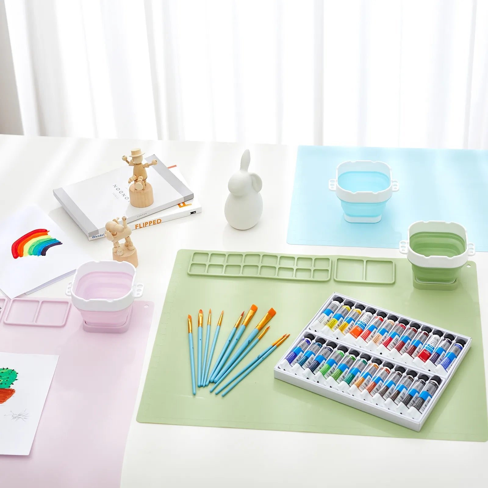 Art supplies, including paint tubes, brushes, and a palette, are on a table.