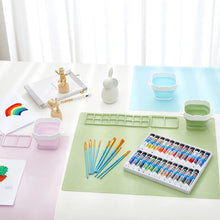 Art supplies, including paint tubes, brushes, and a palette, are on a table.