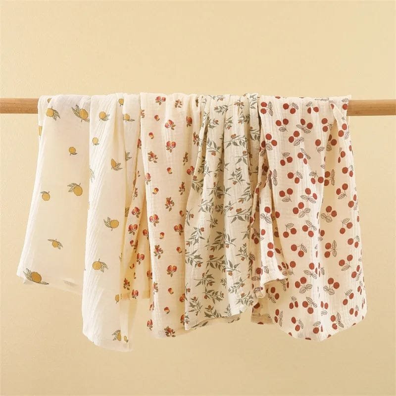 Super Soft Cotton Gauze Muslin Swaddle and Bath Towel, floral-patterned fabric draped over a wooden rod, for newborn swaddling, bath time, and stroller outings.