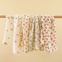 Super Soft Cotton Gauze Muslin Swaddle and Bath Towel, floral-patterned fabric draped over a wooden rod, for newborn swaddling, bath time, and stroller outings.
