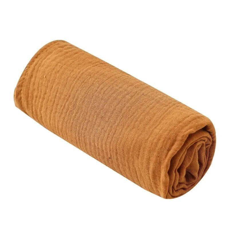 Super Soft Cotton Gauze Muslin Swaddle and Bath Towel, rolled-up brown towel, for newborn swaddling, bath time, and stroller outings.