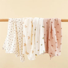 Super Soft Cotton Gauze Muslin Swaddle and Bath Towel, two baby swaddles with floral and rainbow patterns hanging, for newborn swaddling, bath time, and stroller outings.