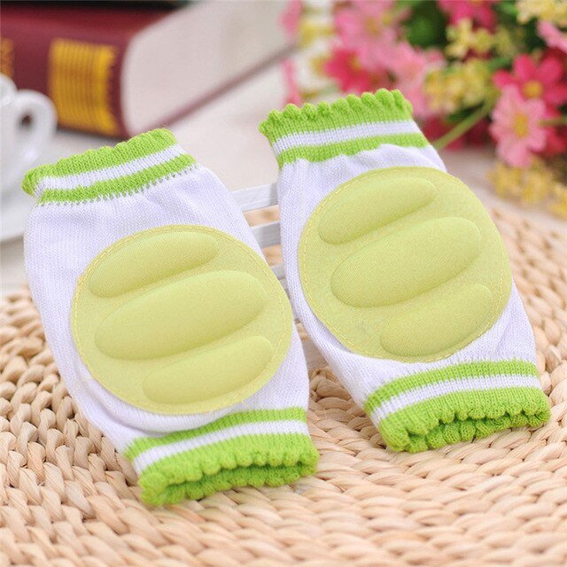 Pair of green and white knee pads on a woven surface.