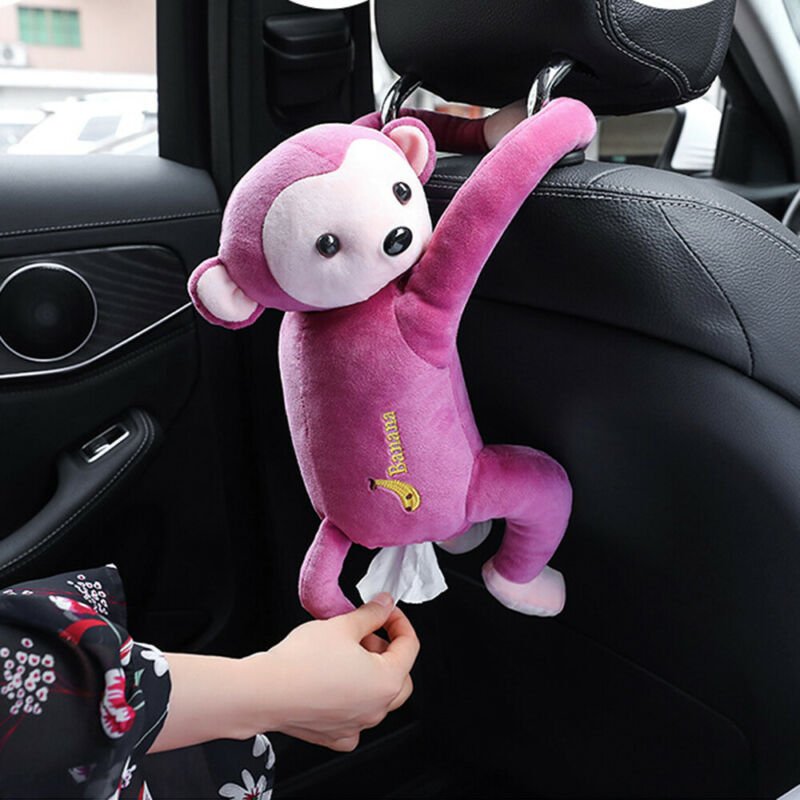Pink monkey-shaped car tissue holder hanging from a car's headrest.