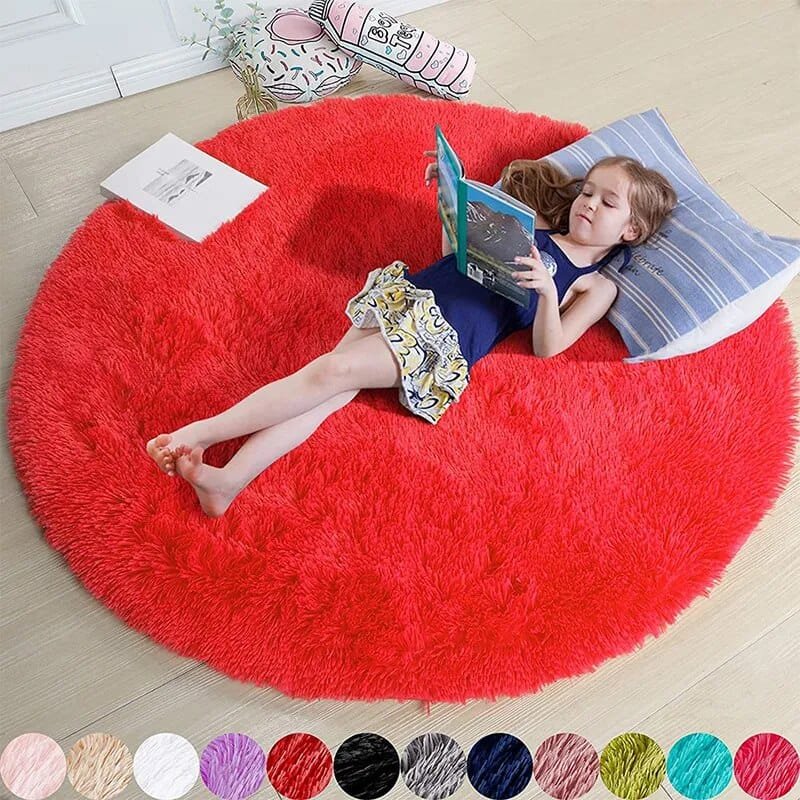 Child reading a book on a large red fluffy rug in a room.