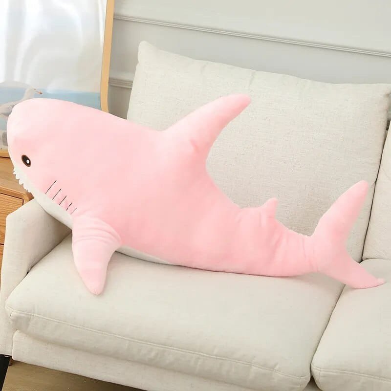Pink shark-shaped pillow on a beige couch