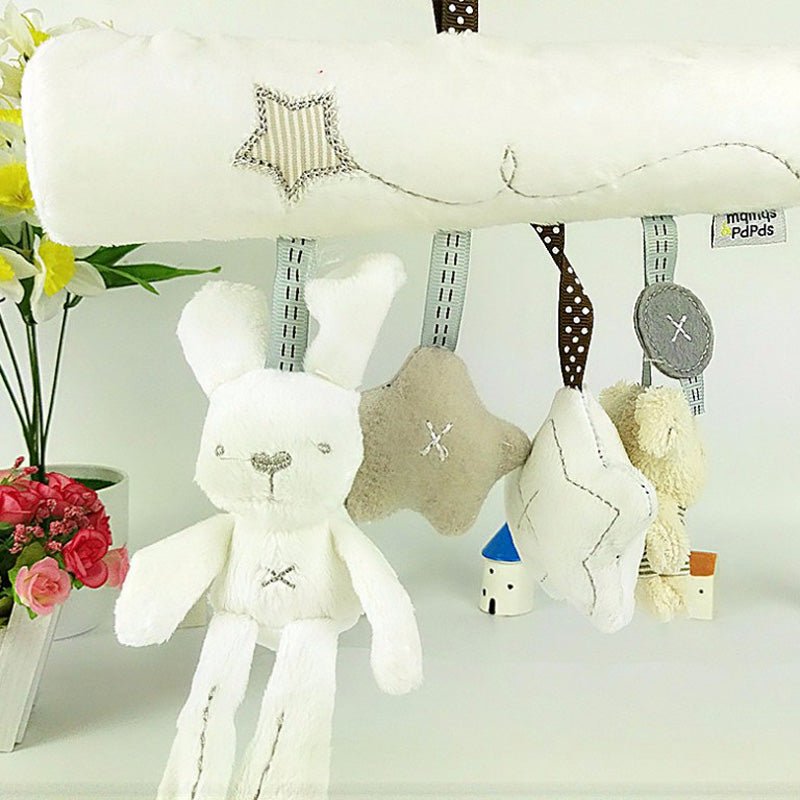 Collection of soft toys including a rabbit, star, and bear on a white surface with flowers in the background.
