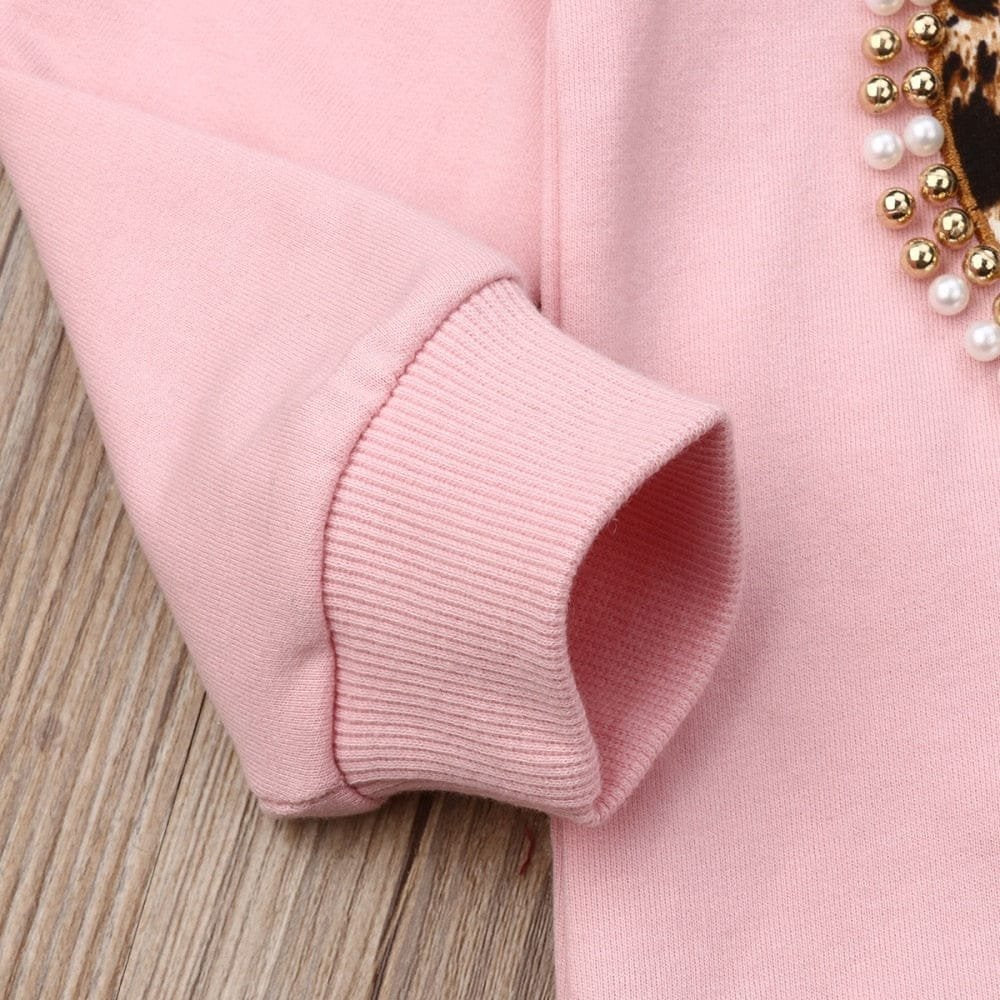Close-up of a pink sweater with a decorative sleeve on a wooden surface