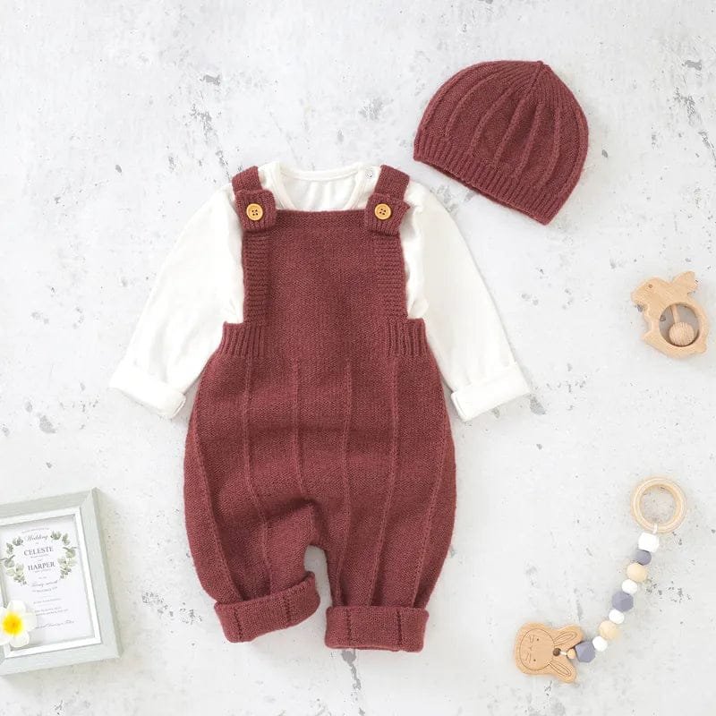 Knitted baby romper and hat set on a light gray surface with toys around