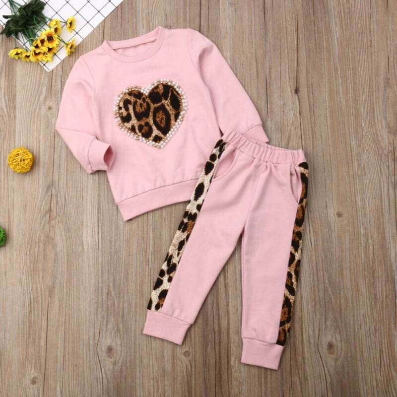 Pink sweatshirt and pants set with leopard print heart design on a wooden surface.
