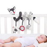 Baby lying in a crib with various animal-themed rattles hanging above.