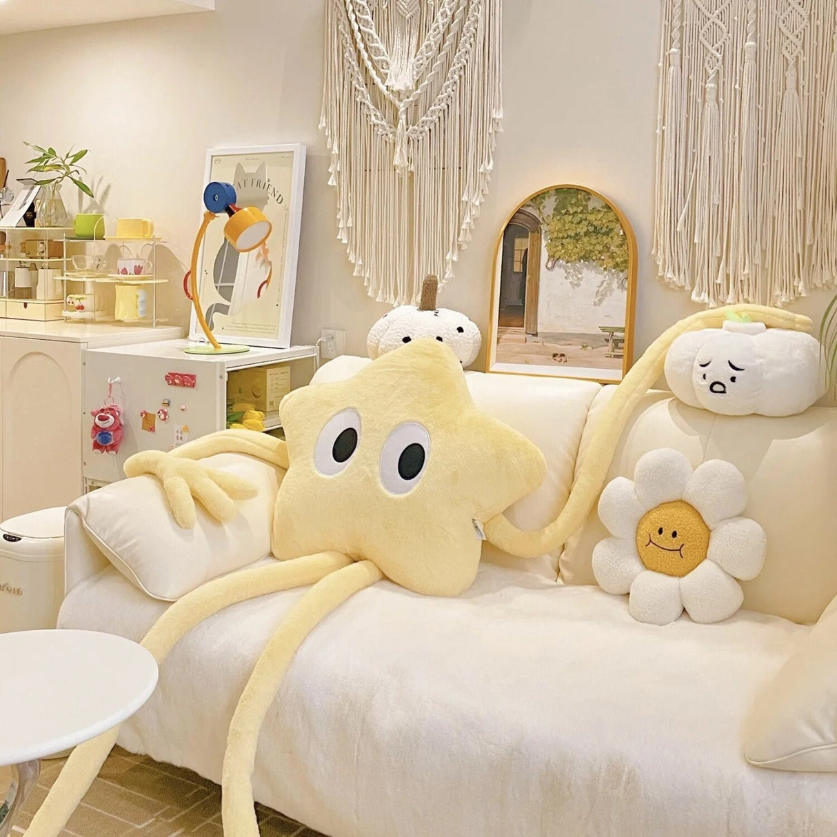Decorative pillows shaped like a star, cloud, and flower on a white sofa in a room with a mirror and lamp.