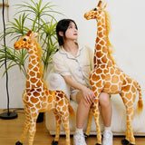 Woman sitting on a couch with two large plush giraffes in a room with plants.