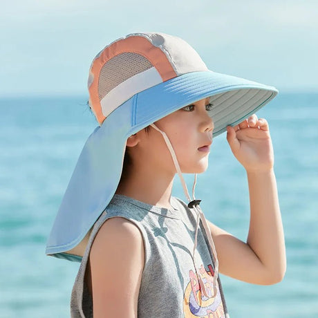 Child wearing a colorful sun hat with a beach background