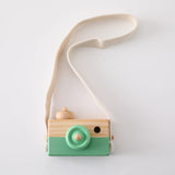 Wooden toy camera with a green base and beige top on a white background
